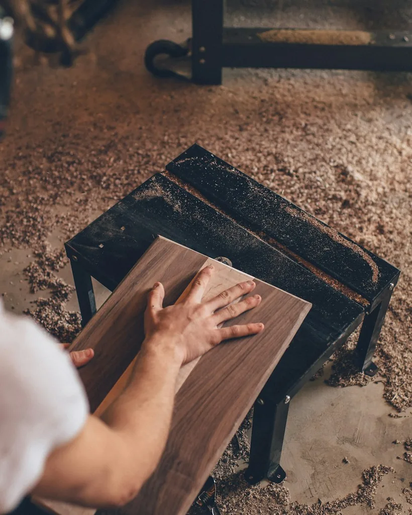 Manos trabajando sobre una tabla de madera durante una tarea de restauración