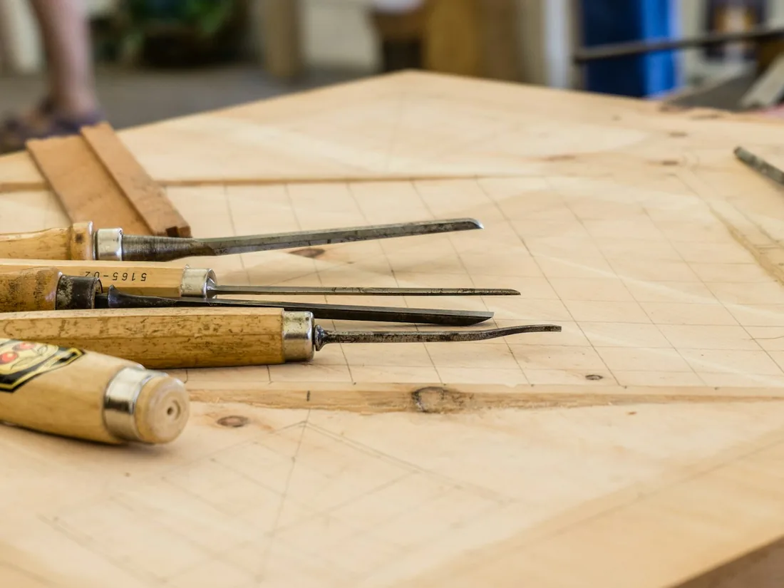 Herramientas de carpintería y restauración dispuestas sobre un banco de madera de taller